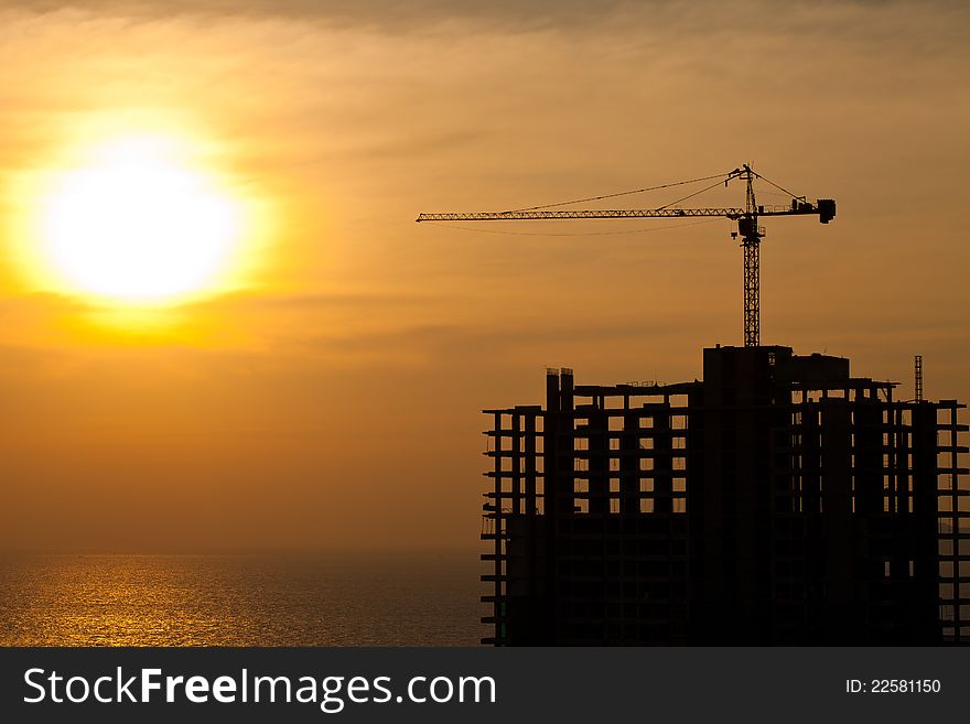 Industrial construction cranes and building silhouettes with sunset