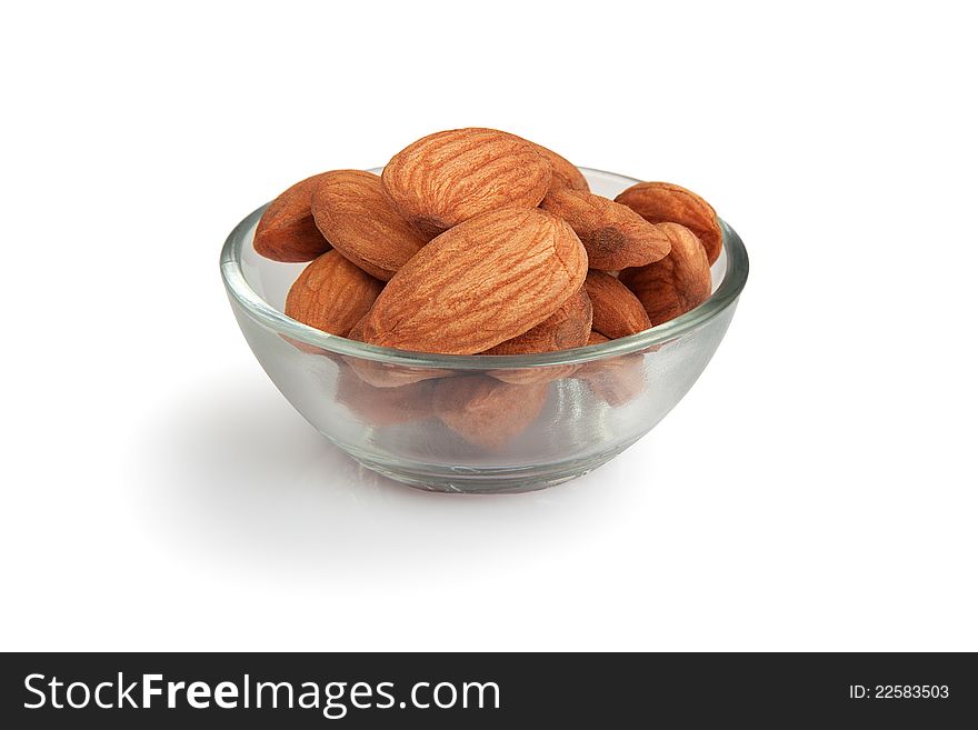 Pile of  almonds in transparent glass small bowl isolated over white background