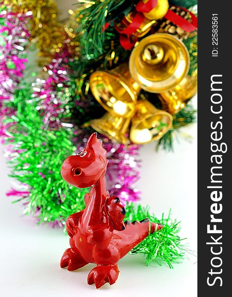 Small decorative ceramic dragon against Christmas tree tinsel and bells. Small decorative ceramic dragon against Christmas tree tinsel and bells