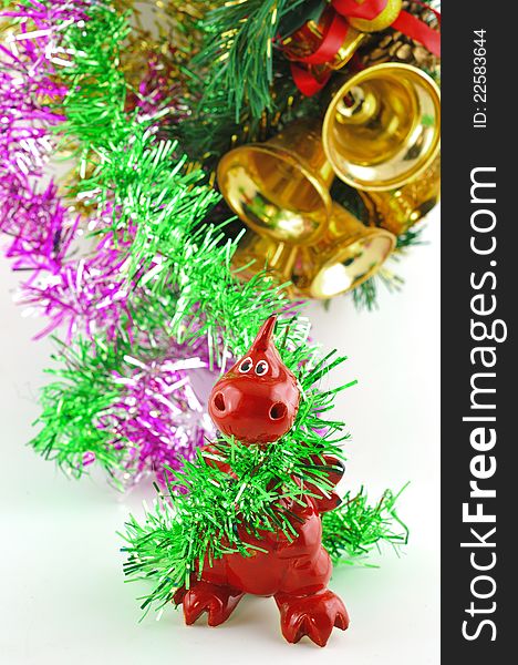 Small decorative ceramic dragon against Christmas tree tinsel and bells. Small decorative ceramic dragon against Christmas tree tinsel and bells
