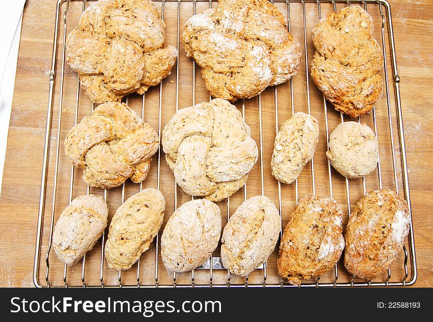 Six cereal and flours buns cooling on a metal rack. Six cereal and flours buns cooling on a metal rack