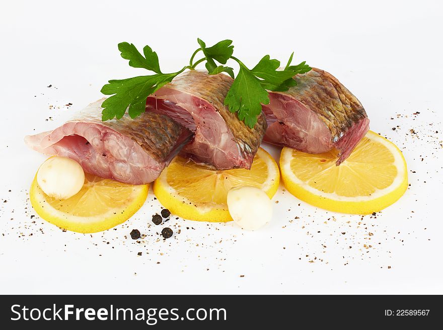 Cutting of crude fish on a lemon and black pepper on the white