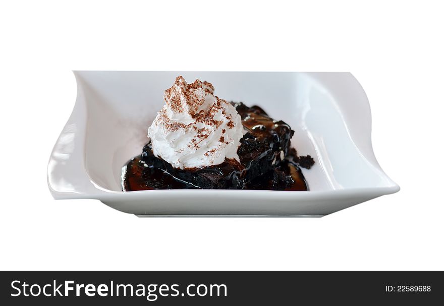 Brownie cake served with chocolate sauce and whipped cream. Brownie cake served with chocolate sauce and whipped cream
