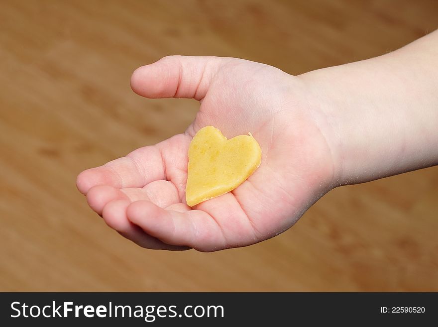 Heart cut out of the dough on child hand