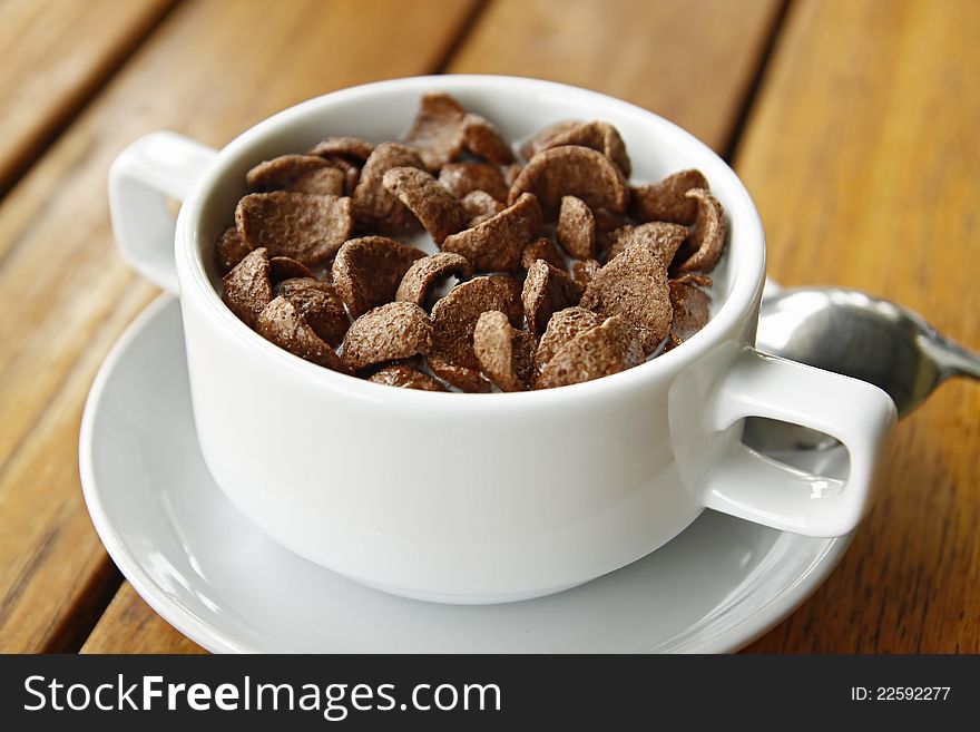 Cocoa cereal in white cup on a wood table