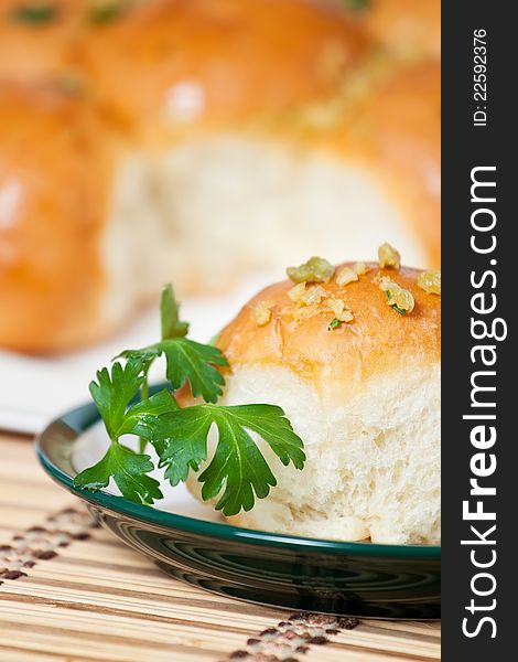 Single bun with garlic pieces on a plate decorated with parsley leaves