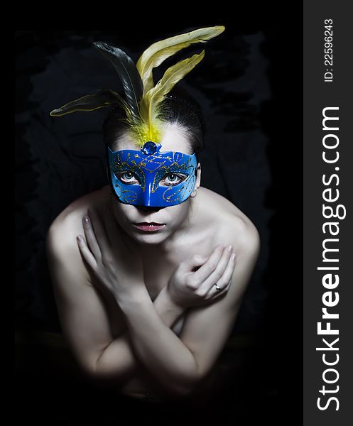 Girl in carnival mask with feathers on a dark background. Girl in carnival mask with feathers on a dark background