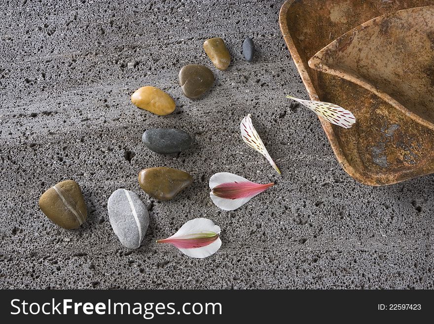 Stones, petals and recipient on a textured stone. Stones, petals and recipient on a textured stone