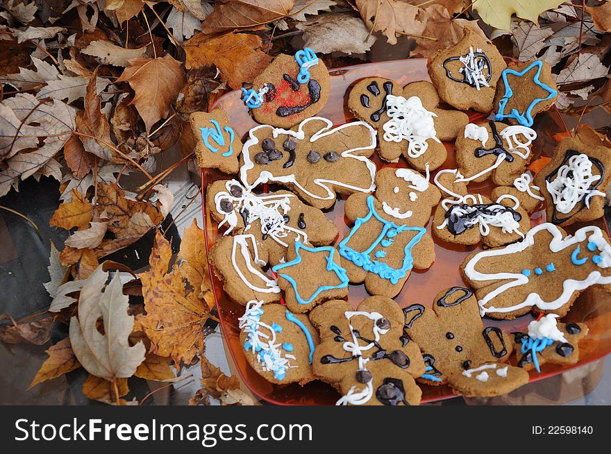 A platter of homemade gingerbread cookies next to a pile of fall leaves.