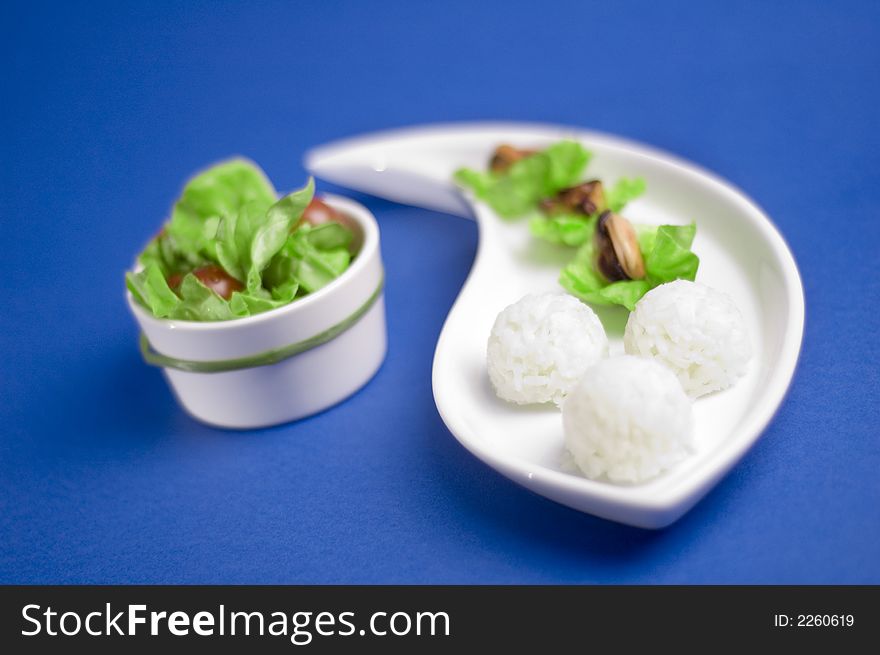 Shells with rice and salad on the dark blue background