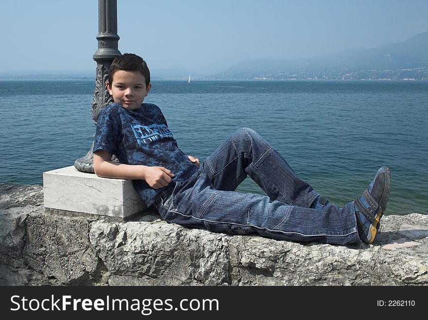 Cute boy hanging around on a wall to pose for the shot. Cute boy hanging around on a wall to pose for the shot