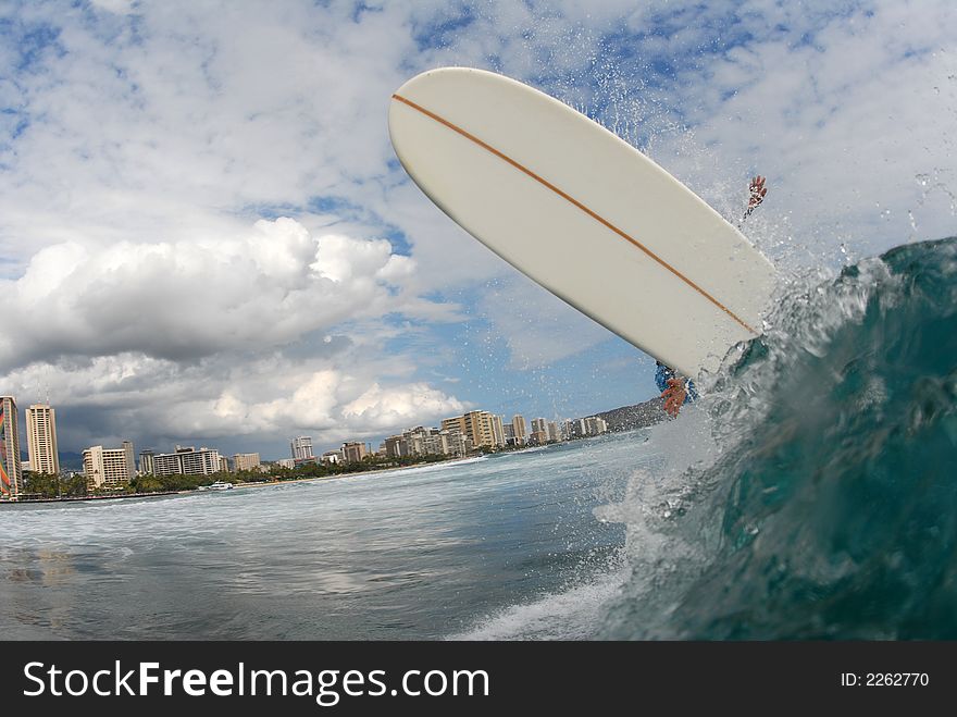 A longboard surfer doing a huge frontside off the lip in hawaii.