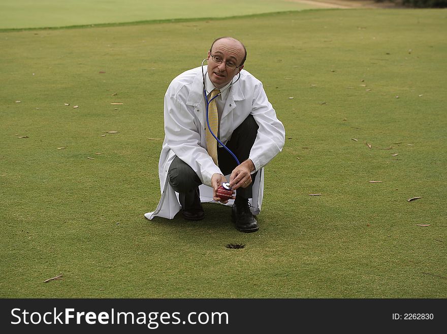 Medical doctor on the golf course checking a red cricket ball with his stethoscope, in the hope of helping you improve your game. Medical doctor on the golf course checking a red cricket ball with his stethoscope, in the hope of helping you improve your game