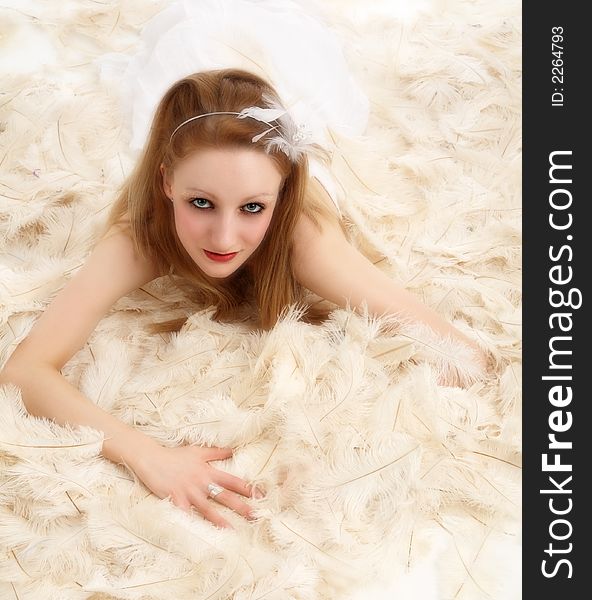 Young woman lying on hundreds of ostrich feathers. Young woman lying on hundreds of ostrich feathers