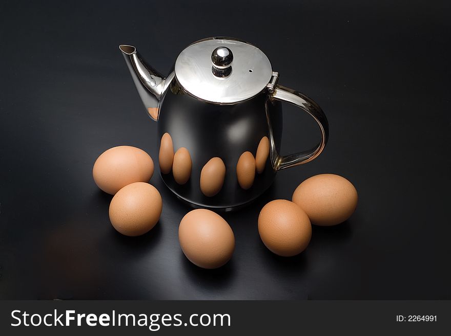 Kettle with some brown eggs on a black background. Kettle with some brown eggs on a black background