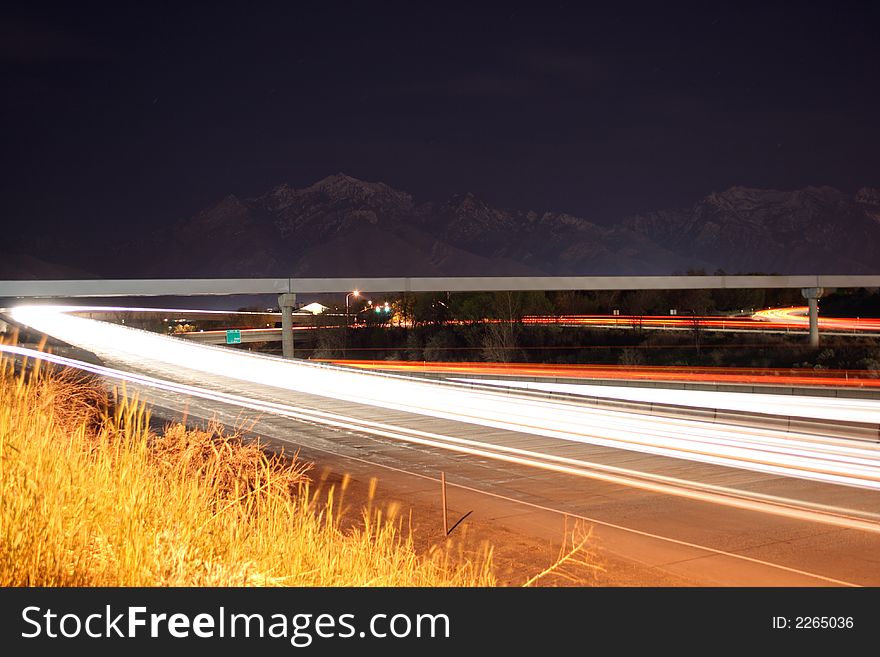 A scene from near an on ramp of highway where cars and trucks zoom past. A scene from near an on ramp of highway where cars and trucks zoom past