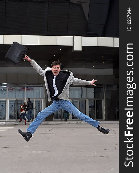 Businessman with a portfolio, jumping on a background of office building. Businessman with a portfolio, jumping on a background of office building