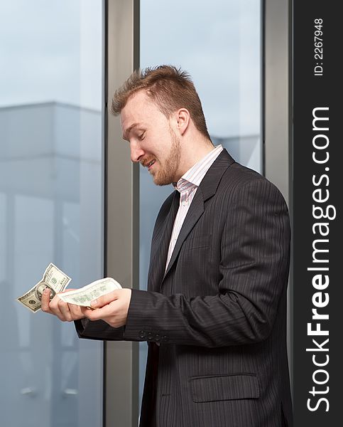 Sad businessman with money in hands on a background of a window. Sad businessman with money in hands on a background of a window