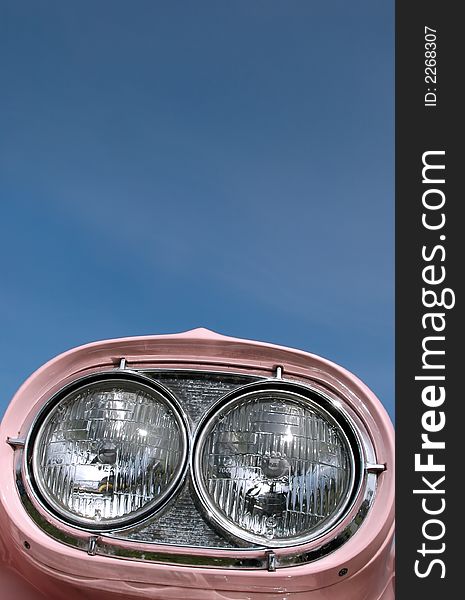 Pink classic car headlamps against blue sky. Pink classic car headlamps against blue sky