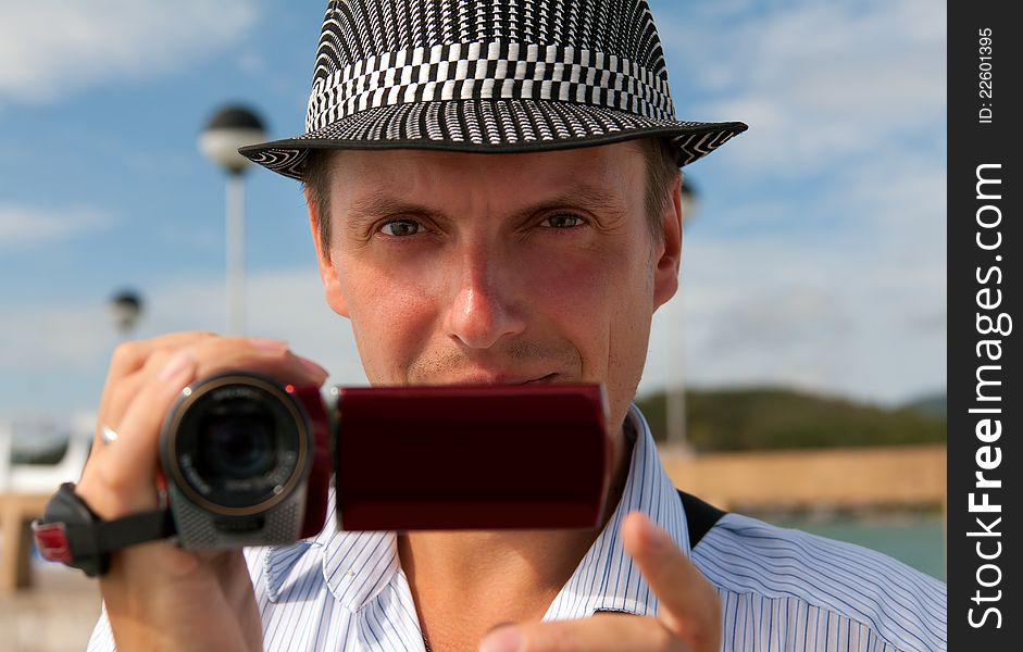 Man in a hat with a camera looking to the frame