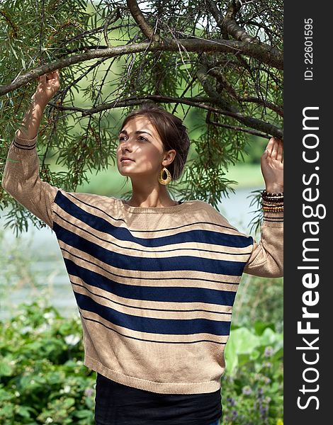 Portrait of a girl in a beige striped sweater with a tree