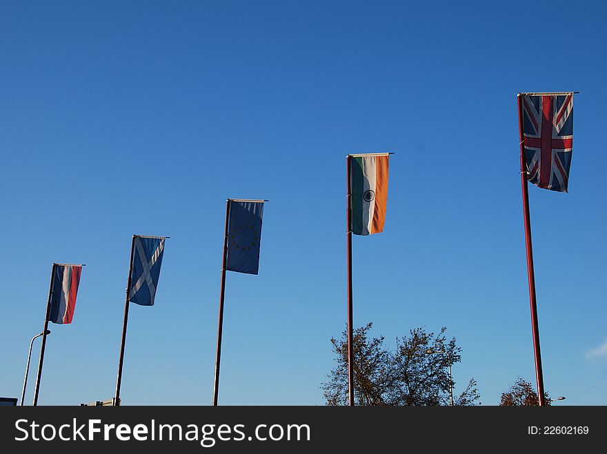A variety of national flags fly from flag poles outside a hotel