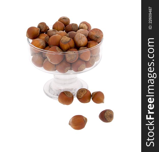 Hazelnuts in a glass vase on a matter of background