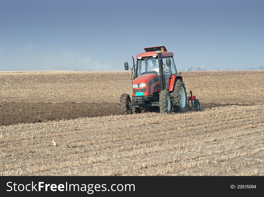 Red Tractor Plowing in autumn