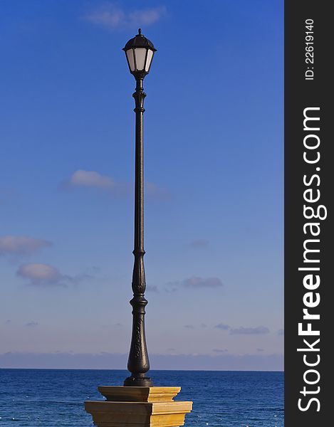 The street lamp against the background of sea and blue sky. The street lamp against the background of sea and blue sky