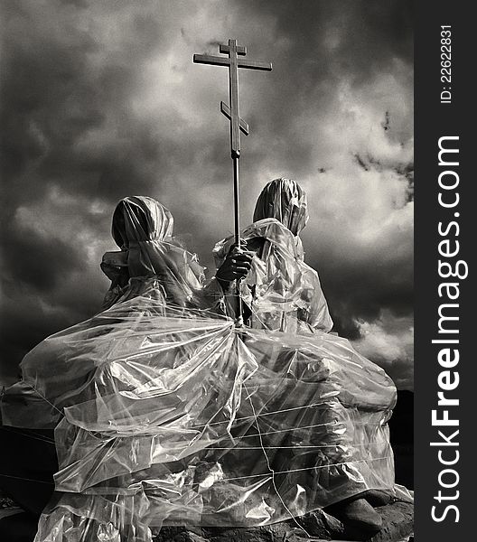 Cross and the religious sculpture closed by plastic wrap against the dramatic sky
