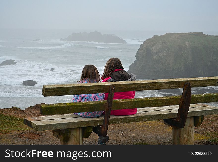 Two girls watching the ocean through the fog. Two girls watching the ocean through the fog