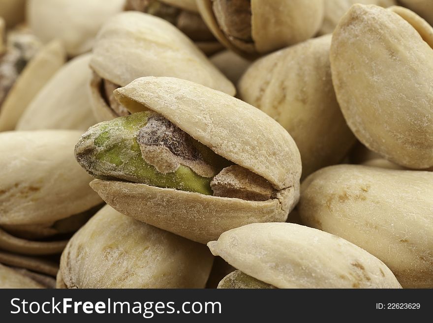 A pile of roasted salted pistachios one close-up showing it's seed. A pile of roasted salted pistachios one close-up showing it's seed