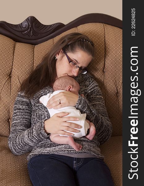 A mother holding her newborn son on the couch in a loving embrace. A mother holding her newborn son on the couch in a loving embrace.