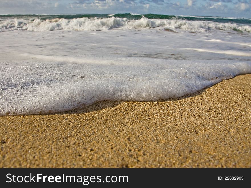 Ground perspective of an incoming tide with foam and golden sand. Ground perspective of an incoming tide with foam and golden sand