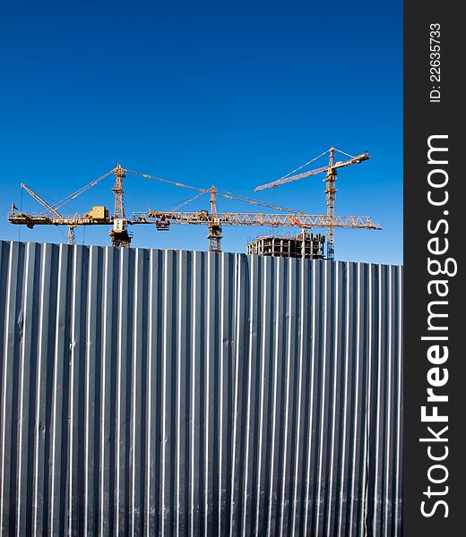 Building cranes for fence on background blue sky