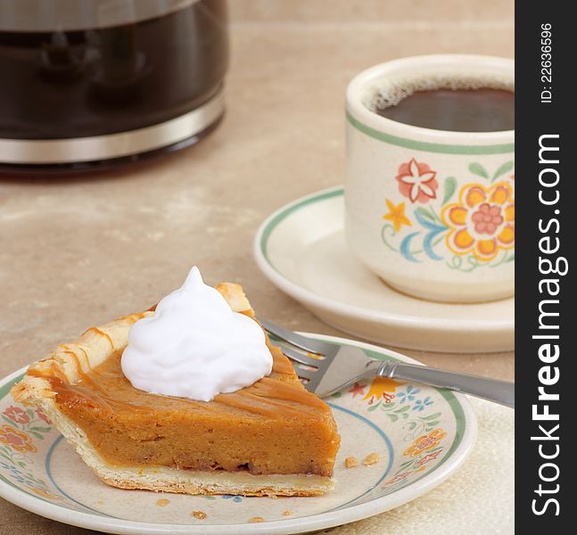 Slice of pumpkin pie topped with whipped cream and coffee. Slice of pumpkin pie topped with whipped cream and coffee