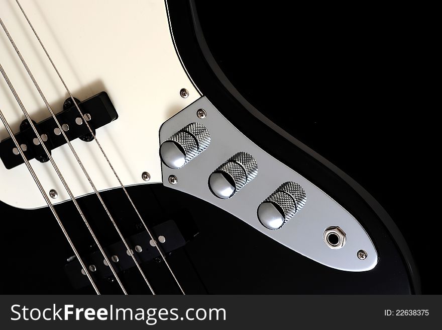 A close up of volume knob of a black electric bass glossy on dark background