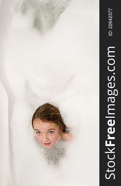 Little girl having fun in a bathtub full of soap foam. Little girl having fun in a bathtub full of soap foam.