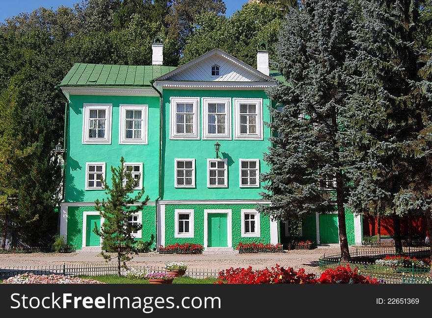 Green mansion surrounded with trees and flowers