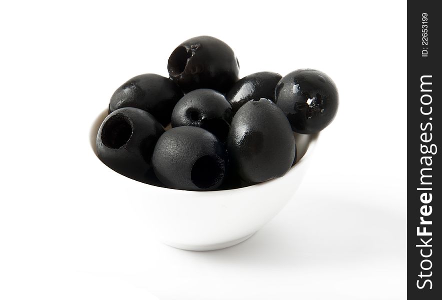 Black olives in a bowl on white