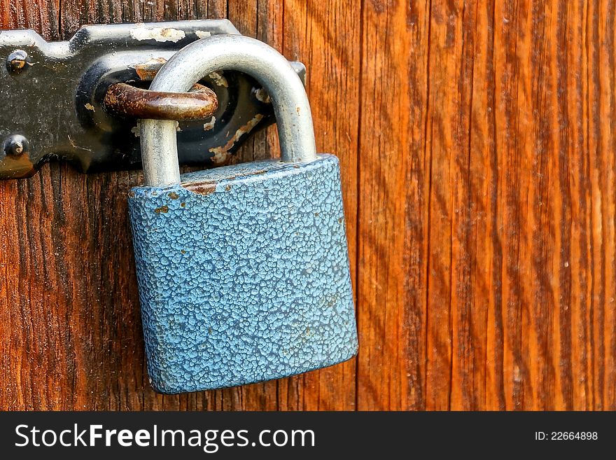 Blue Padlock And Black Rusty Haspa On Wooden Door