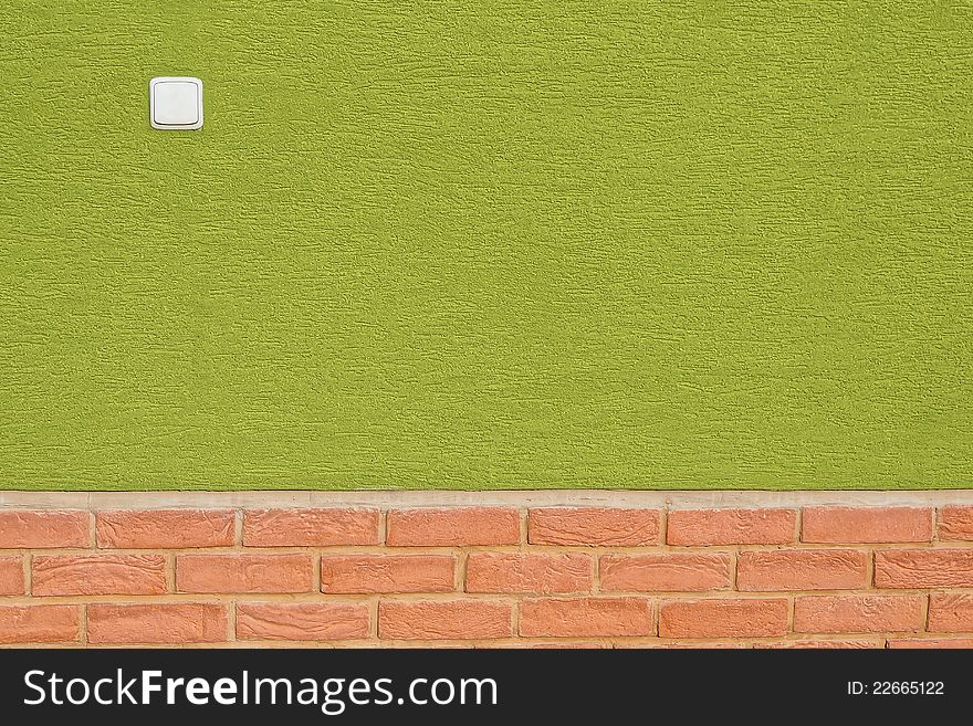 Green wall with bright red bricks on bottom and white light switch. Green wall with bright red bricks on bottom and white light switch