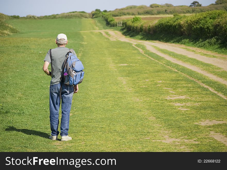 Senior Man Hiking Over Field In Summer