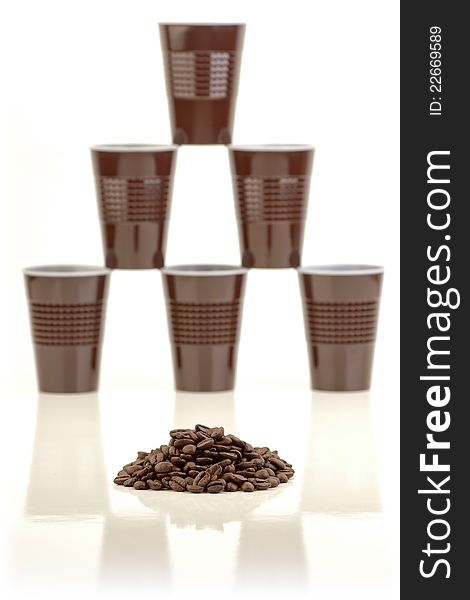 Pile of coffee beans and a stack of plastic cups arranged in the background on white. Pile of coffee beans and a stack of plastic cups arranged in the background on white.