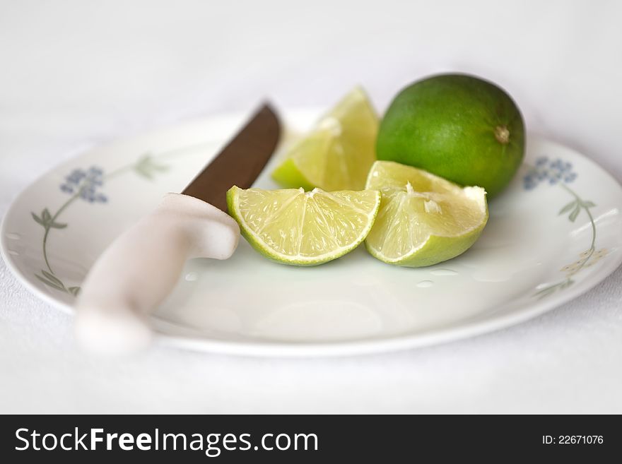 Pieces of cut lime and whole lime on a plate