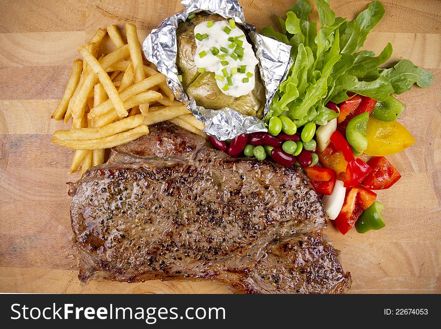 Set of steak with salad, fries and baked potato.