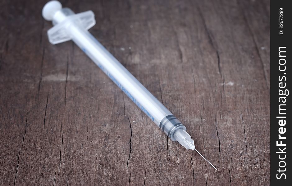 Close up photo of syringe on wooden table
