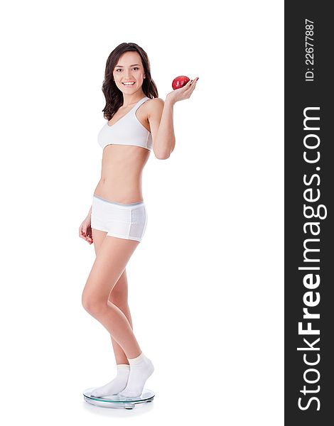 Yound fit girl holding apple standing on scales. Yound fit girl holding apple standing on scales