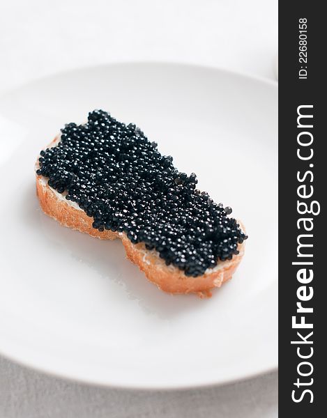 White bread with caviar on a ceramic plate