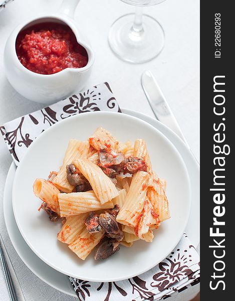 Pasta with meat on a white plate and a thick tomato sauce